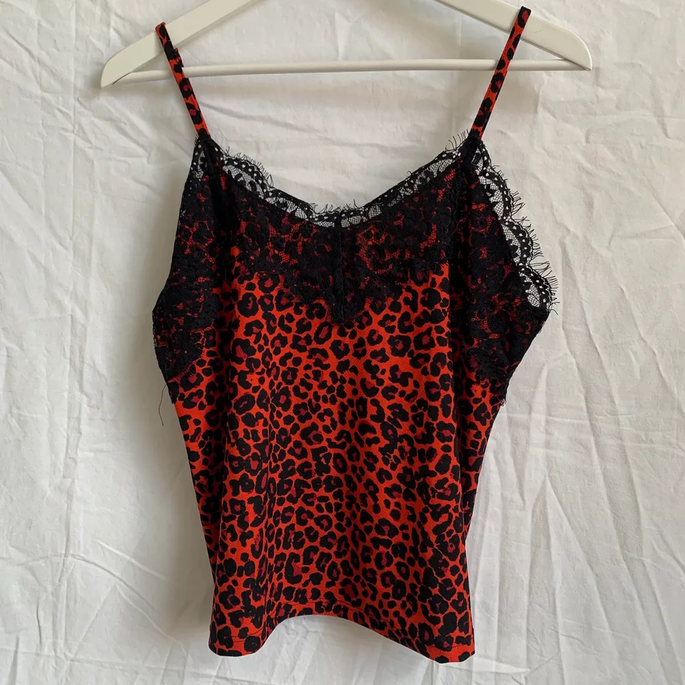 Röd/svart leopardmönstrat linne med svart spets. Är 170 och har oftast S/36. Använt en gång, nyskick! . Toppar.