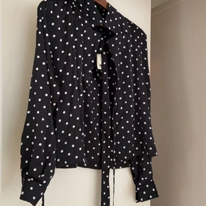 Prickig blus aldrig använd  - Prickig blus med knytband för att markera midjan. Snygg blus som aldrig är använd. Nypris 299 kr. 