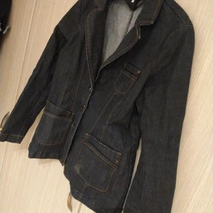 Jeansjacka från Joy. Stl. 42 - Elegant jeansjacka från märket Joy. Fin kvalité och samtidigt väldigt bekväm, alltså inte stel och jobbig. Knappar framtill. Passformen påminner lite om en kavaj liksom den mörkare färgen. Kan passa storlekar mellan 40-42.