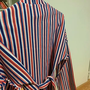 Randig långärmad tröja - En randig långärmad tröja och lite högre i halsen. Den har ett bälte i likadant tyg en fin detalj. 