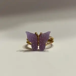 Silverring med gulddetaljer i form av en lila fjäril.