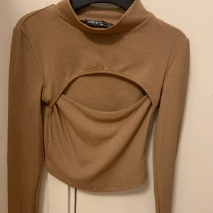 Topp - Topp med en utskärning över bröstet, jättefin färg och i storlek 34/XS🤎. Frakt 45kr