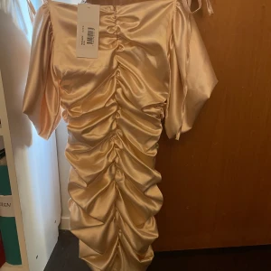 Satinklänning från chiqeulle oanvänd - Storlek S. Prislappen är kvar. Haft klänningen i ca 1 år men aldrig använt. Sitter snyggt på, men inte riktigt min stil!