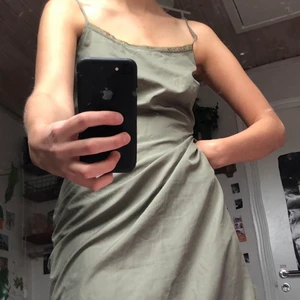 Grön klänning - Grön midiklänning som slutar under knäet på mig ( är 170 cm). Från början tror jag den har varit en underklänning men eftersom den verkligen inte är genomskinlig tycker jag att den fungerar bra som vanligt klänning. 100%polyester. Ena bandet är lite trasigt och går inte att byta längd. Köpte för längesedan för att sy om vilket inte blivit av. Sista bilden visar bäst färgen. Den är mer grön i verkligheten