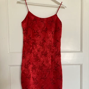 Skimrande drakklänning  - Ett stycke skimrande klänning med drakmönster och spaghetti band till salu! En slits i högra hörnet, innertyg och stängs med dragkedja bak. Köpt här i gruppen men något stor för mig i bystet. Inga anmärkningar förutom att hylsan till dragkedjan är lite defekt, inget som påverkar användningen dock. Blir din för 150 riksdaler + 66 kr spårbar frakt!🐉🐉🐉  Klänningens längd: 81 cm Axel till axel: 37 cm  Midja: cirka 38 cm Slits: 16 cm