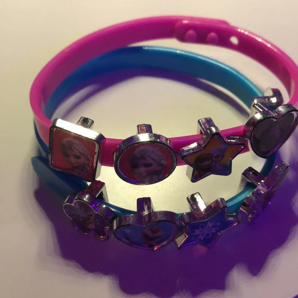 Två armband ett blått och ett rosa tillsammans 9 detaljer på armbanden som man kan ta av. Man kan ändra 3 stycken steg på armbanden så det blir olika storlekar på dom.. Accessoarer.