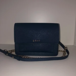 DKNY axelremsväska  - Marinblå DKNY axelremsväska med tre små fack och ett stort. Nyskick.