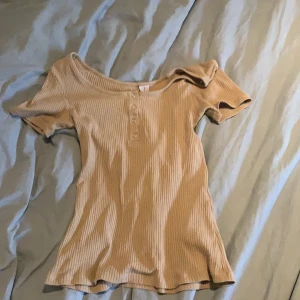 Beige t-shirt med knappar - Denna är aldrig använd, nästan helt nyköpt. Frakten ingår i priset.