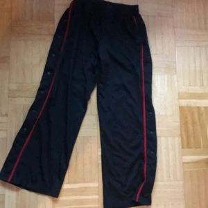 Sweatpants med knappar  - Oanvända! Säljes pga för långa (är 1,54) Skönt material! Trendiga & bekväma sweatpants med fickor frampå, knappar längs sidorna & vida nertill. Helsvarta, förutom den röda randen. Inga hål eller andra skavanker!