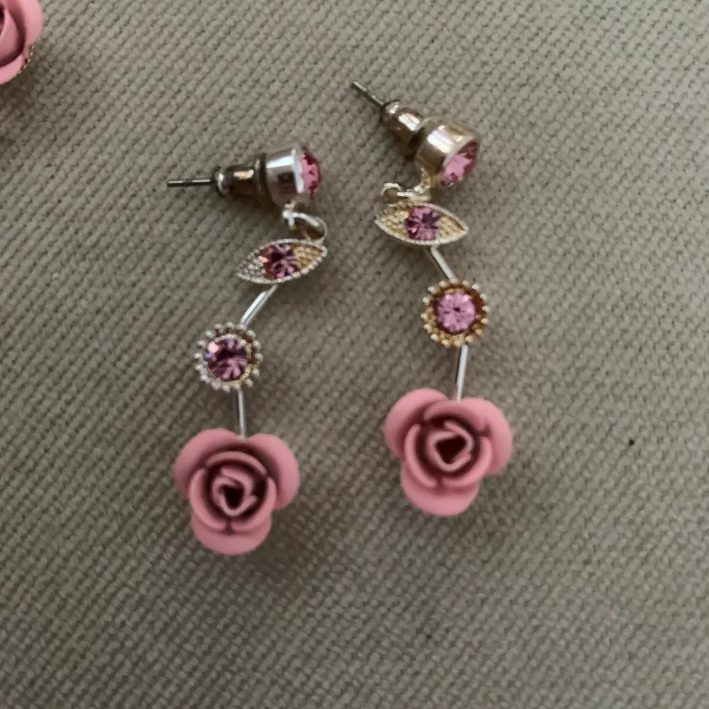 Ett sett med jättefina örhängen och halsband med rosa rosor, väldigt gulligt och i bra skick och knappt använda, frakt tillkommer. Accessoarer.