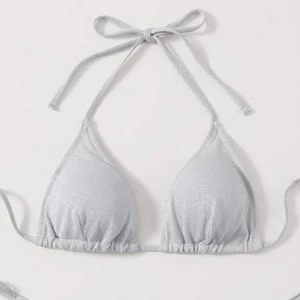 glittrig bikini - Säljer denna så fina silverglittriga bikiniöverdel pga förliten🥺, den är helt oanvänd! stl M men passar mer en Xs mindre S. den är ej genomskinlig och har inlägg som går att ta ut!