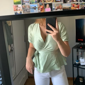Grön topp  - Grön fin topp från Vero Moda som endast är använd 1 gång. Storlek M och är i ett glansigt material. Knytning vid sidan. 