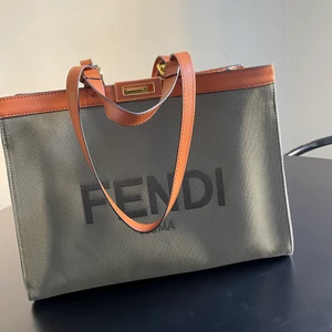 Fendi Roma bag  - Grön/grå väska i canvas med läderdetaljer från Fendi. 2 små svarta prickar på baksidan av väskan som man säkert kan få bort hos kemtvätten.. (därav priset 2000kr) Annars så är väskan i mycket bra skick! Väskan har även längre band så man kan bära den på axeln. Perfekt storlek 40x30 cm så väskan rymmer mycket som tex dator, block, böcker osv.. Väskan kommer med dustbag, har ej kvitto! 