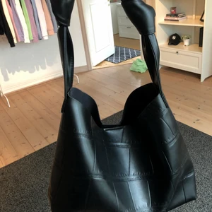 Väska - Säljer denna fina svarta fake ”läder/ormskinn” väska från shein. Bra kvalitet med fina ”knutar” på handtaget. Kanterna är endast avklippta men inte på ett fult sätt eller något som kan gå sönder. Orginalpriset var 116 kr. Säljer då den inte kommer till användning eller är min stil, aldrig använd. Tar swish 🥰 Köparen står för frakt