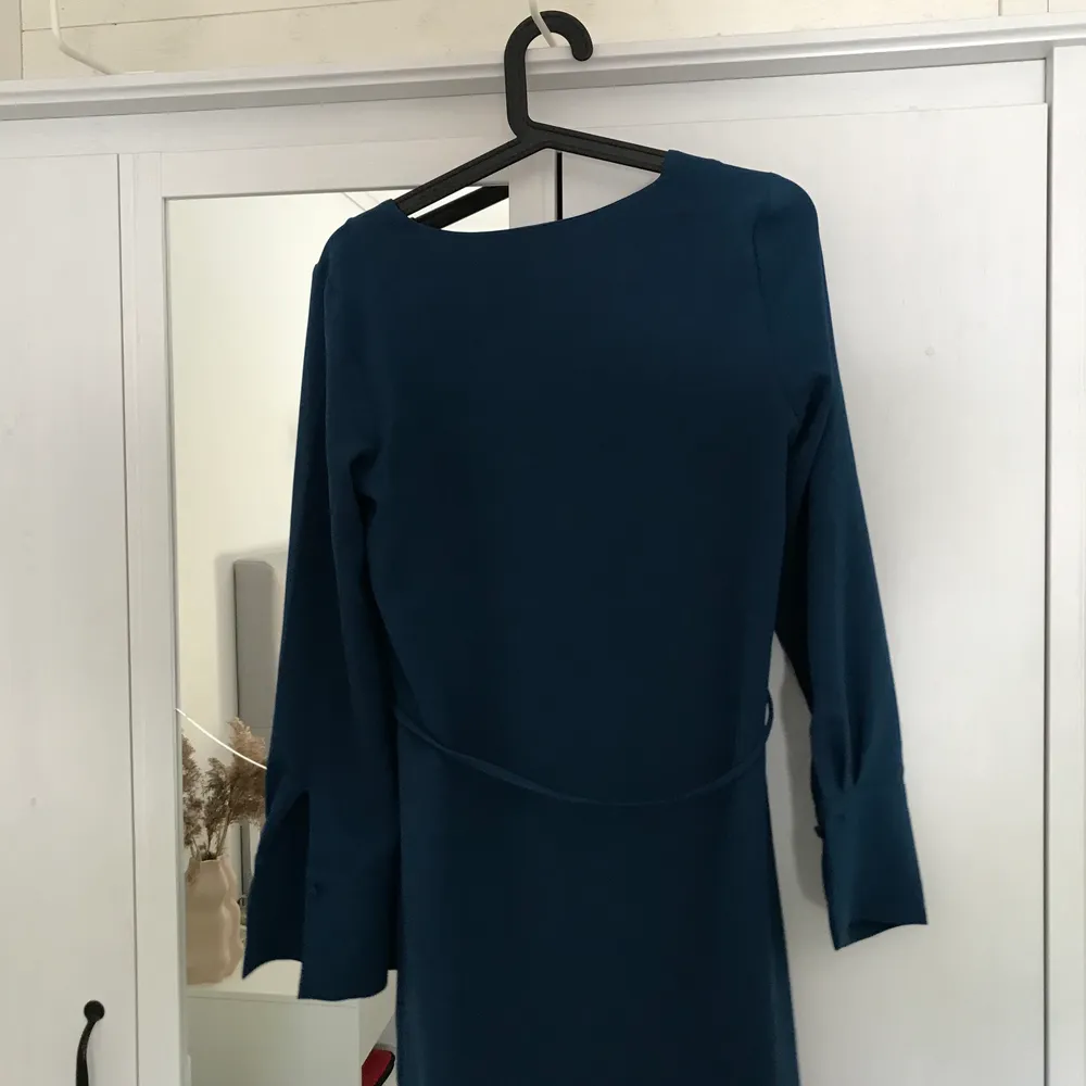 Jättefin mörkblå klänning från H&M. V- ringad, knyte runt magen och knappar vid ärmslutet. Nästintill oanvänd, priset kan diskuteras. Köparen står för frakten. . Klänningar.