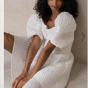 Klänning med djup rygg - Vit klänning med puffärmar, djup rygg och ett fint & detaljerat material. Den är bekväm och man kan tro att ärmarna lätt trillar ner men de sitter väldigt bra! Använd 1 gång och har en liten fläck på baksidan. Annars är den som ny!