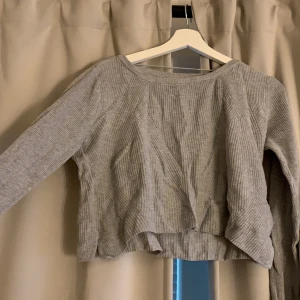 Vermoda tröja - Kort grå stickad tröja med långa armar och slits på sidan.