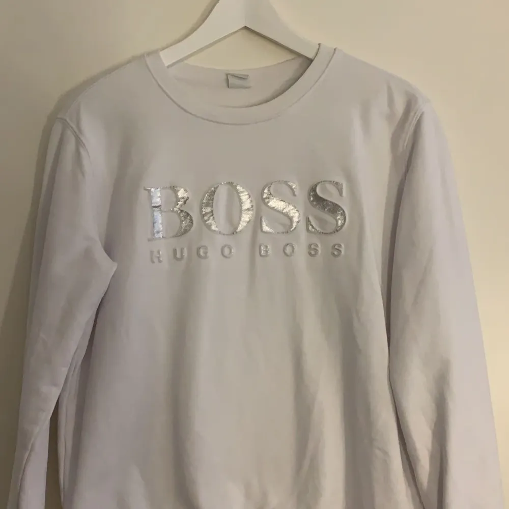 Vit Hugo boss tröja med silver detaljer. Har använt den ca 4 gånger och har inga fläckar eller hål. Köpte den för 800kr men säljer den för 500kr. Tröjor & Koftor.