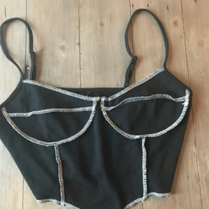 Svart linne med vita sömmar  - Ett svart linne med vita sömmar. Köparen står för frakten 