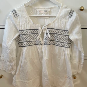 Odd Molly - Vit blus med blåa broderade detaljer från Odd Molly. Storlek 0, motsvarade XS. Blusen är i mycket fint skick. Nypris ca 1200 kr, jag säljer för 150 kr.