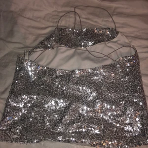 Silvrigt glitterlinne paljettlinne - Så snyggt silvrigt paljettlinne från nly trend. Korsad rygg. Strl 34 men passar upp till 38. 