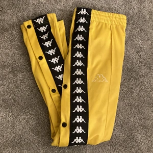 Kappa byxor med knappar💛 - Säljer nu mina gula kappabyxor med en tår i ögat då jag tycker dom är sjukt snygga men är för små på mig.  Dom är köpt på Junkyard för två år sedan för 500kr. Det är unisex strlk XS. Har både knappar på sidorna sedan är det fickor och snören på insidan i midjan. Knappt använda då dom vart små men inte velat sälja, som nyskick. Köparen står för frakten🌟