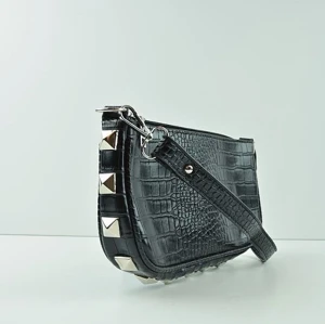 New Me💙 by M.E.J UF - En svart ormskinsväska med fyrkantiga nitar längst sömmarna. Väskan har ett innerfack samt silvriga detaljer.  