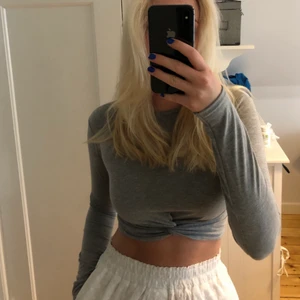 Grå långärmad croptop - Supermjuk croptop med långa ärmar och en fin detalj fram. Sitter verkligen så bra på! Helt oanvänd med prislapp kvar, har en likadan redan, (gillade den min så mycket att jag köpte en till), men blev att jag inte behövde använda denna. Strl S. 😇😇