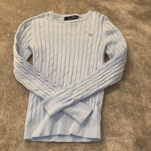 Kabelstickad gant tröja - En ljusblå kablestickad tröja från gant. Används inte längre. Buda från 200kr eller köp direkt för 250kr. Köparen står för frakt!
