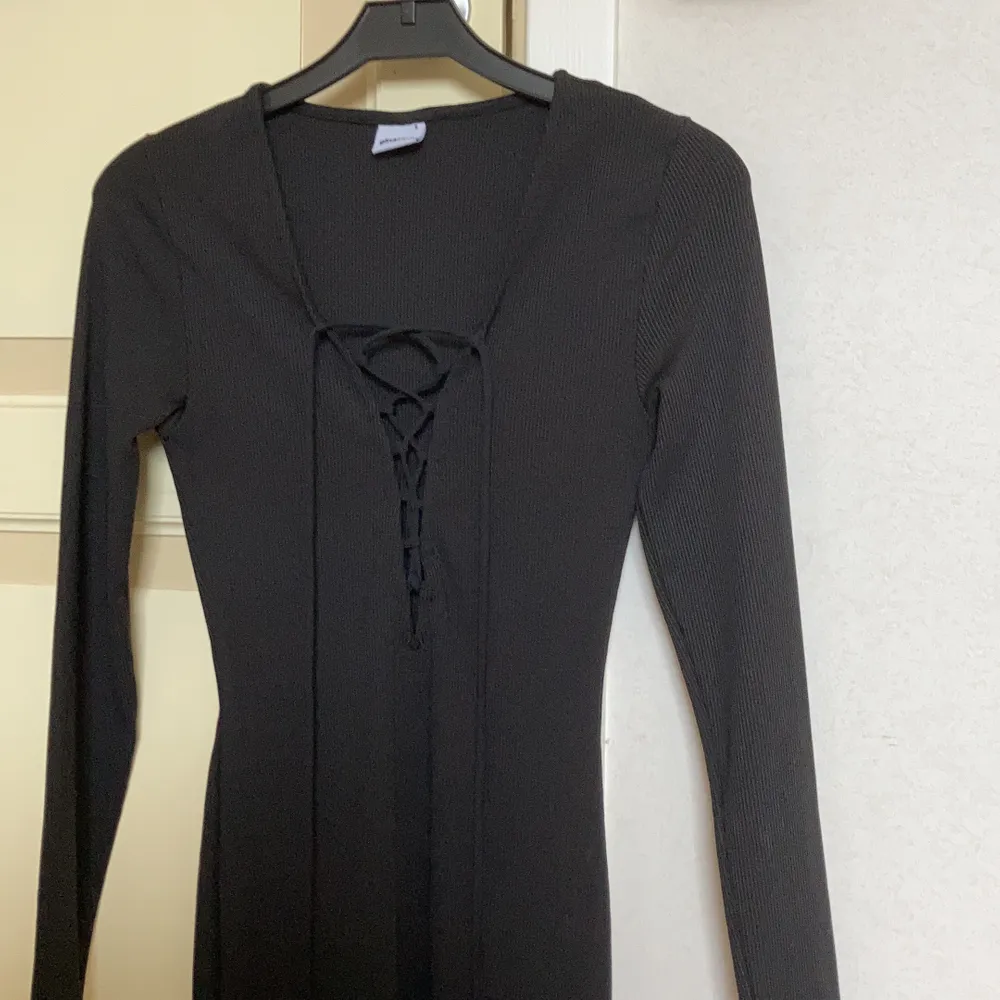 En svart, ribbad klänning från Gina Tricot i strl S. Låg urringning med snörning, tight passform.. Klänningar.