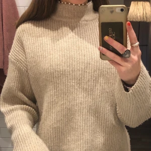 Beige stickad tröja st xs  - Detta är en beige stickad tröja som är köpt på hm. Den jag vita pärlor fast sydda vid halsen.