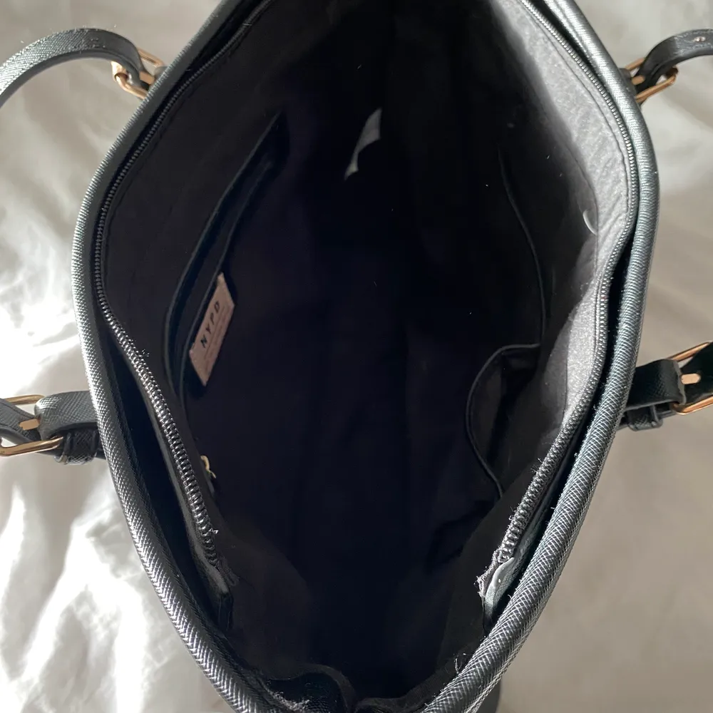 New York Portable Designs väska som är svart med guldiga detaljer.Väskan har dragkedja och inuti ett litet fack med dragkedja och sedan 2 andra små fack . Den har en liten skada som jag visar på en av bilderna men inget som syns vid användning. Köpt för 500kr, köparen betalar för frakten . Väskor.