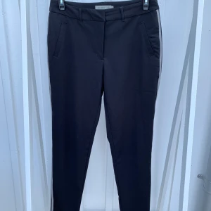 Svarta kostymbyxor från Vero Moda - Svarta kostymbyxor från Vero Moda i ett tunt material och med fina virkade revärer. Använda ett fåtal gånger och är i nyskick. 