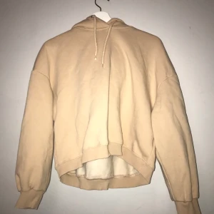 Hoodie - En cropad beige hoodie med ett pytte litet stygn i för den gick sönder men de syns knappt, det sitter i ryggen(säljer billig pågrund av de) annars är den i bra skick och den är använd en gång.