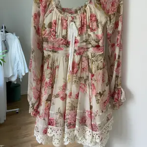 Super söt blommig Gyaru stil klänning från Liz Lisa (japanskt märke). Det är en ”one size” men är som en 34. Rätt puffig kjol med många lager undertill, knytning framtill, skira armar och resår i ryggen. Rätt kort i modellen