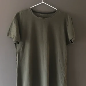 Mörkgrön t-shirt - Säljer mörkgrön t-shirt med tryck på ryggen, använd max 5 tillfällen.