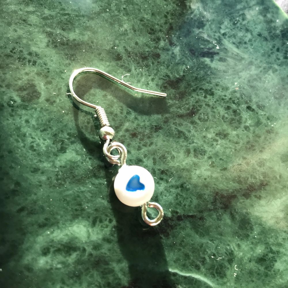 Ett par örhängen som har en pärla med ett mörkblått hjärta på sig!!. Accessoarer.