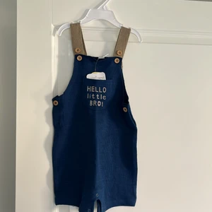 Barn kläder storlek 12-18mån - Jättesöt outfit för barn med text i marin blå och bruna toner. Kan knäppas av/på vid benen och det finns knappar på sidorna också. Den är 100% bombull. Köper man 3 plagg och mer  blir frakten gratis.