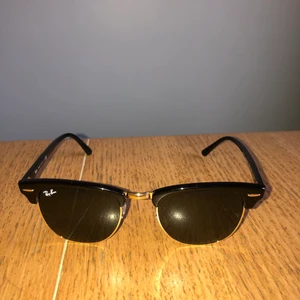 Rayban Clubmaster Svart/guld - Ett par sköna solglasögon ifrån välkända Ray-Ban. Säljs knappt använda på grund av att jag helt enkelt har för många solglasögon. Har som sagt knappt använt dessa och tror att de kan komma till bättre användning hos någon annan