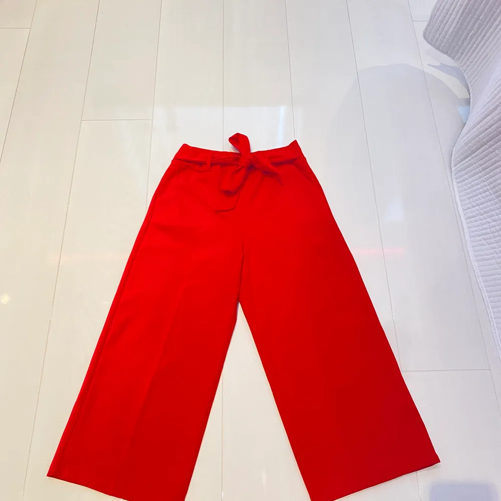Korta röda byxor med band i midjan, liten skråma på vänster ben annars fint skick. Lite utsvängda. Jeans & Byxor.