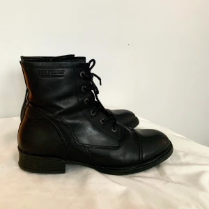 Nya svarta kängor/ fodrade/ nyskick/ stl: 40 - Fodrade kängor från märket Ten Points. Köpta på Nilson Shoes. Nypris: 1 500 kr, använda 2 gånger. I blankt läder med filtfoder. Håller värmen bra i kallt klimat, men andas även vid varmare temperaturer. Stängs med en dragkedja och dras åt genom snörning.