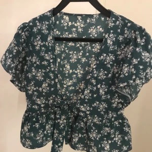 Söt blommig blus  - Blusen är inte använd och är super söt. Den är mörkgrön med vita små blommor. 