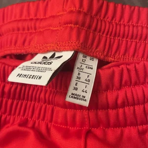 Addidas byxor röda - Säljer ett par byxor i bra skick användt dom få talls gånger, sitter som M/L, dom har knappar vid sidan på var ben som går att knäppa up, köpte dom för i 729kr.