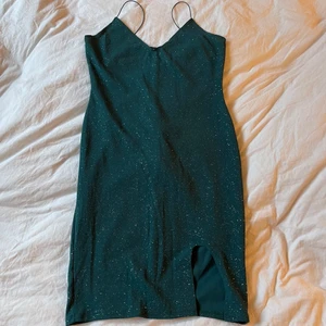 Mörkgrön klänning - Grönklänning med glitter och en slits. Baktill är det ”räfflat” vid rumpan. Väldigt fin, bra kvalitet. Använd 1 gång. Storlek L men skulle säga M  Frakt tillkommer✨