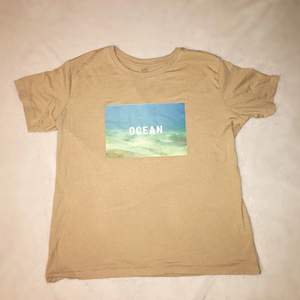 En sandfärgad t-shirt med tryck. Aldrig använd (förutom på bilden). Storlek L (unisex). Fraktalternativ väljer köparen. Meddela mig vid fler frågor!😊