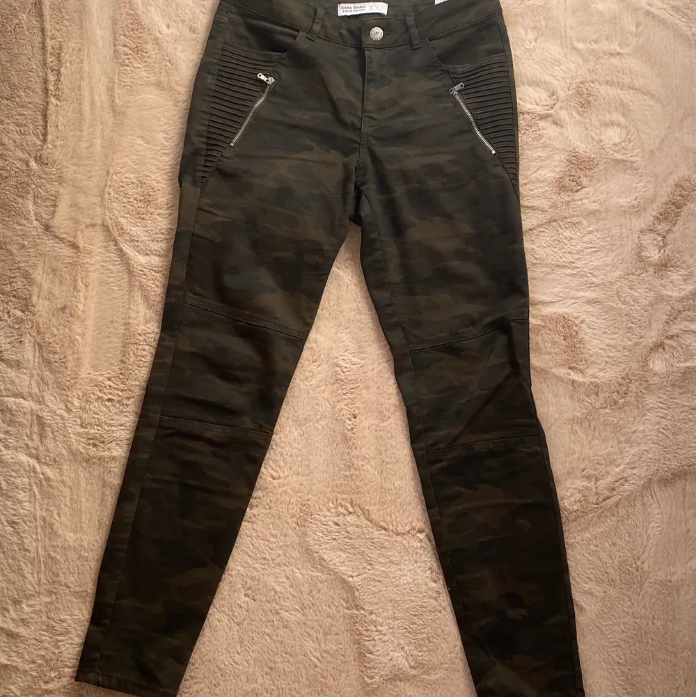 Mörkgröna camoflage byxor i strecight material från zara som är lågmidjade med dragkedja fickor på sidorna . Jeans & Byxor.