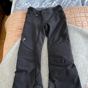 Peak performance, täckbyxor  - Ett par skidbyxor/täckbyxor från Peak performance i storlek 34. Superfint skick!