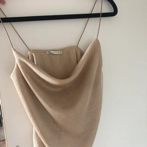 Festligt guldig topp - En lite festligare guldig topp från Nelly som slutar lite högre upp än midjan. 