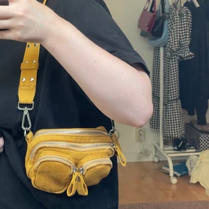 Gul/orange shoulderbag  - Säljer denna gul/orange axelväskan i fejmocka. Det är en liten modell på väskan. Den är näst intill oanvänd och är i nyskick! 💕💕