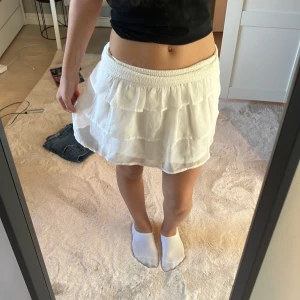 Vit kjol från BikBok - Säljer en söt vit kjol från BikBok i storlek XS. Kjolen har en elastisk midja och volangdetaljer som ger en fin och luftig känsla. Perfekt för varma dagar!